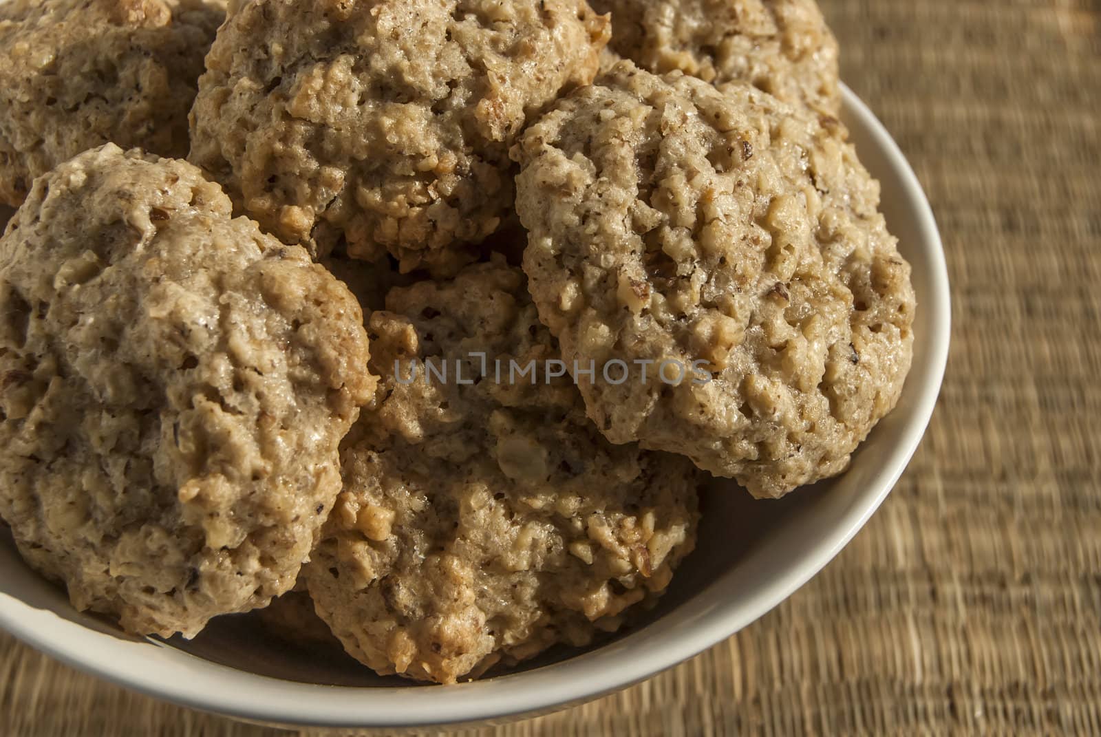 Homemade oatmeal cookies in bowl on reed mat closeup