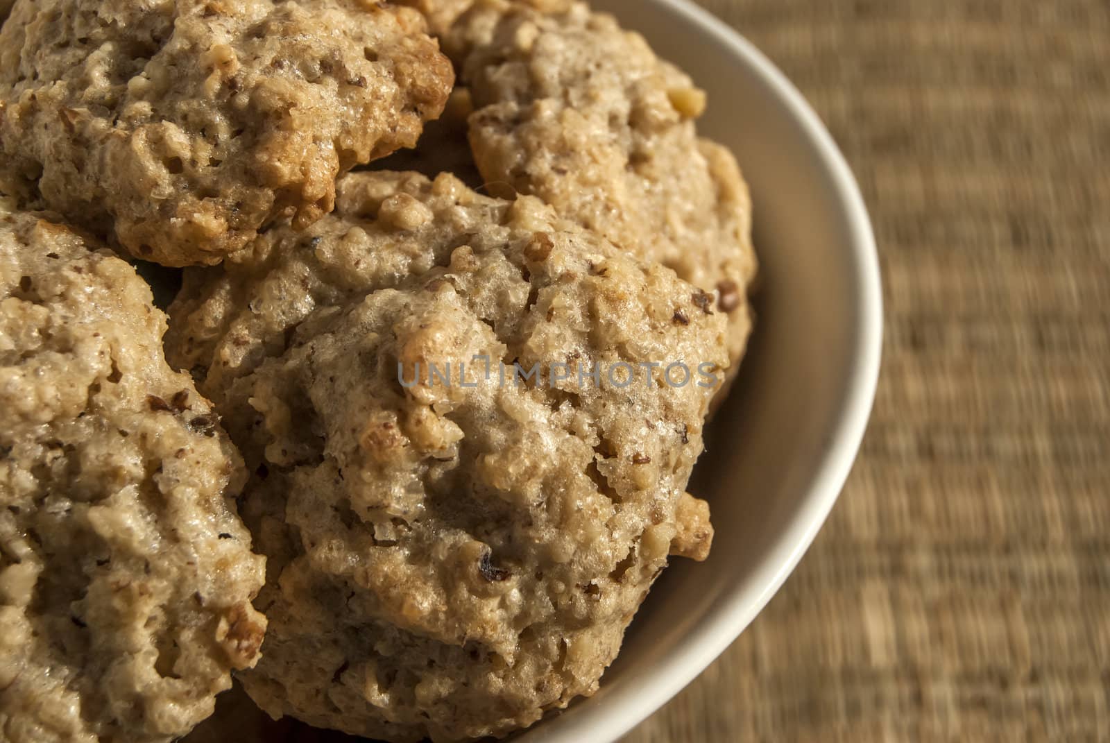 Homemade oatmeal cookies in bowl on reed mat closeup