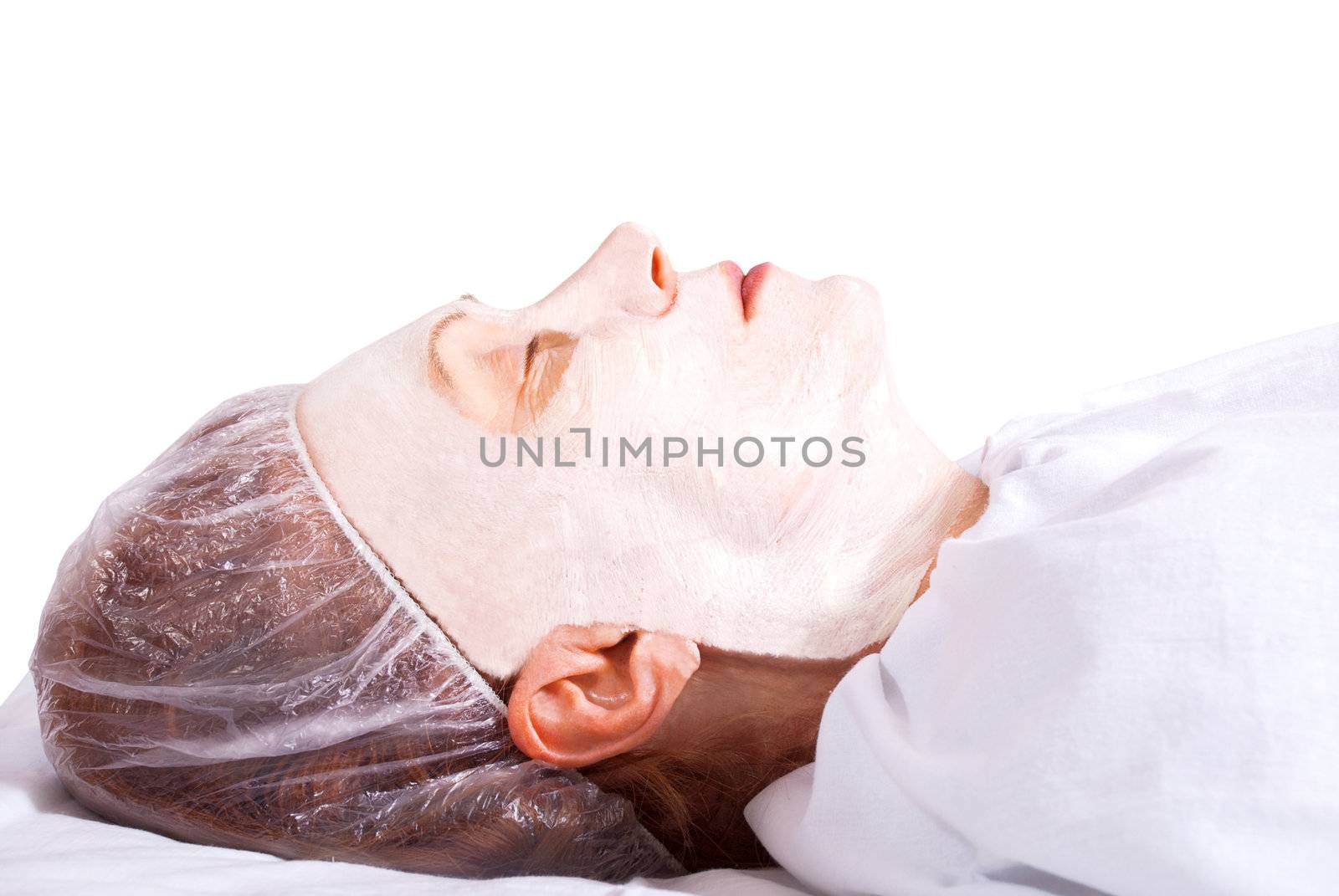 Beautiful woman lying with facial mask on the white background.