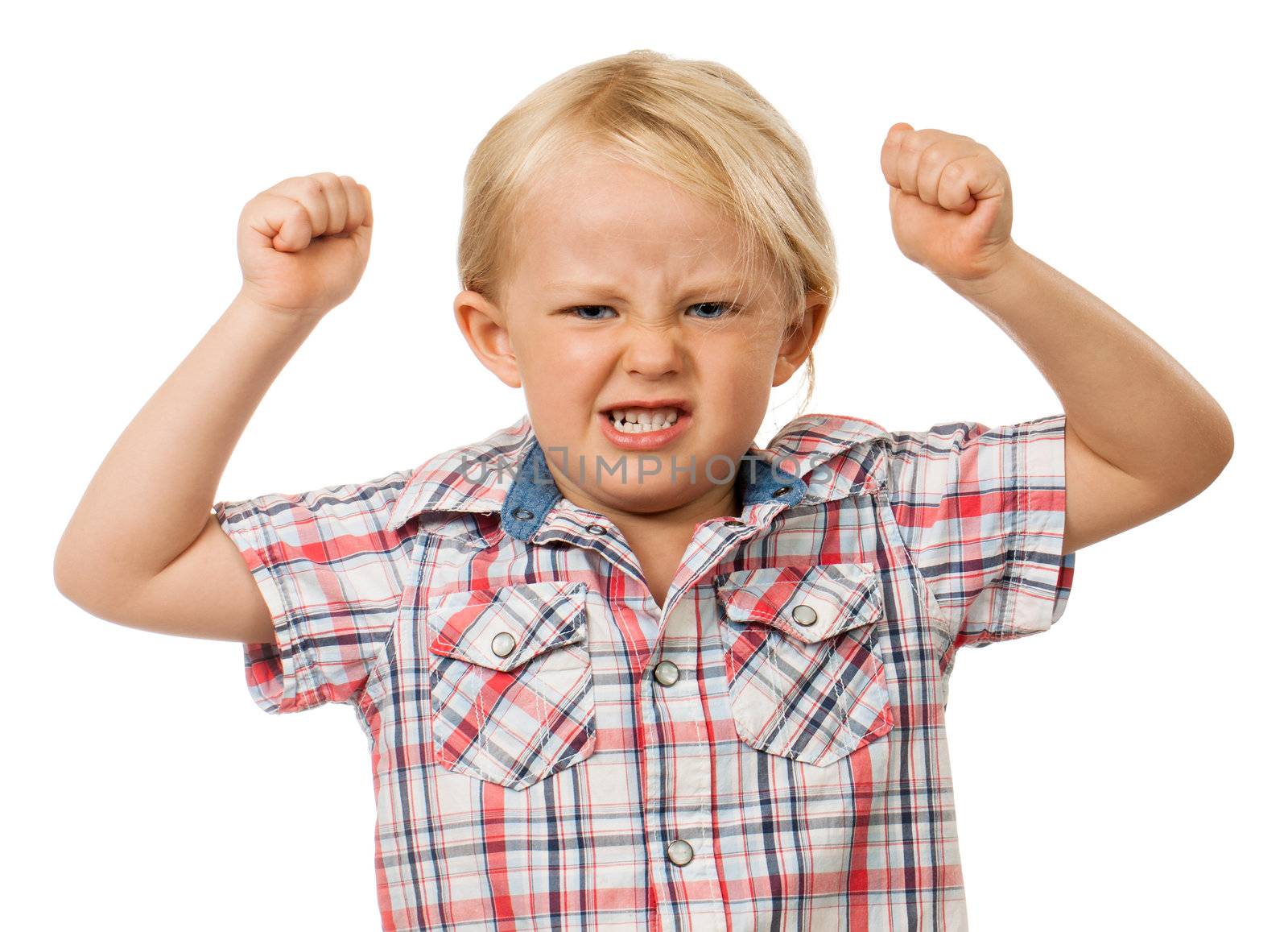 A frustrated and angry young boy with fists raised in the air and pulling a face. Isolated on white.