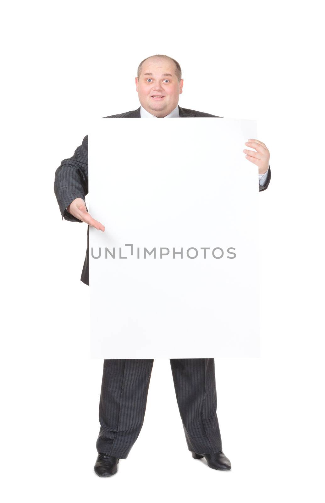 Cheerful overweight stylish business man in a suit holding up a blank white sign and pointing to it with his finger on a white studio background