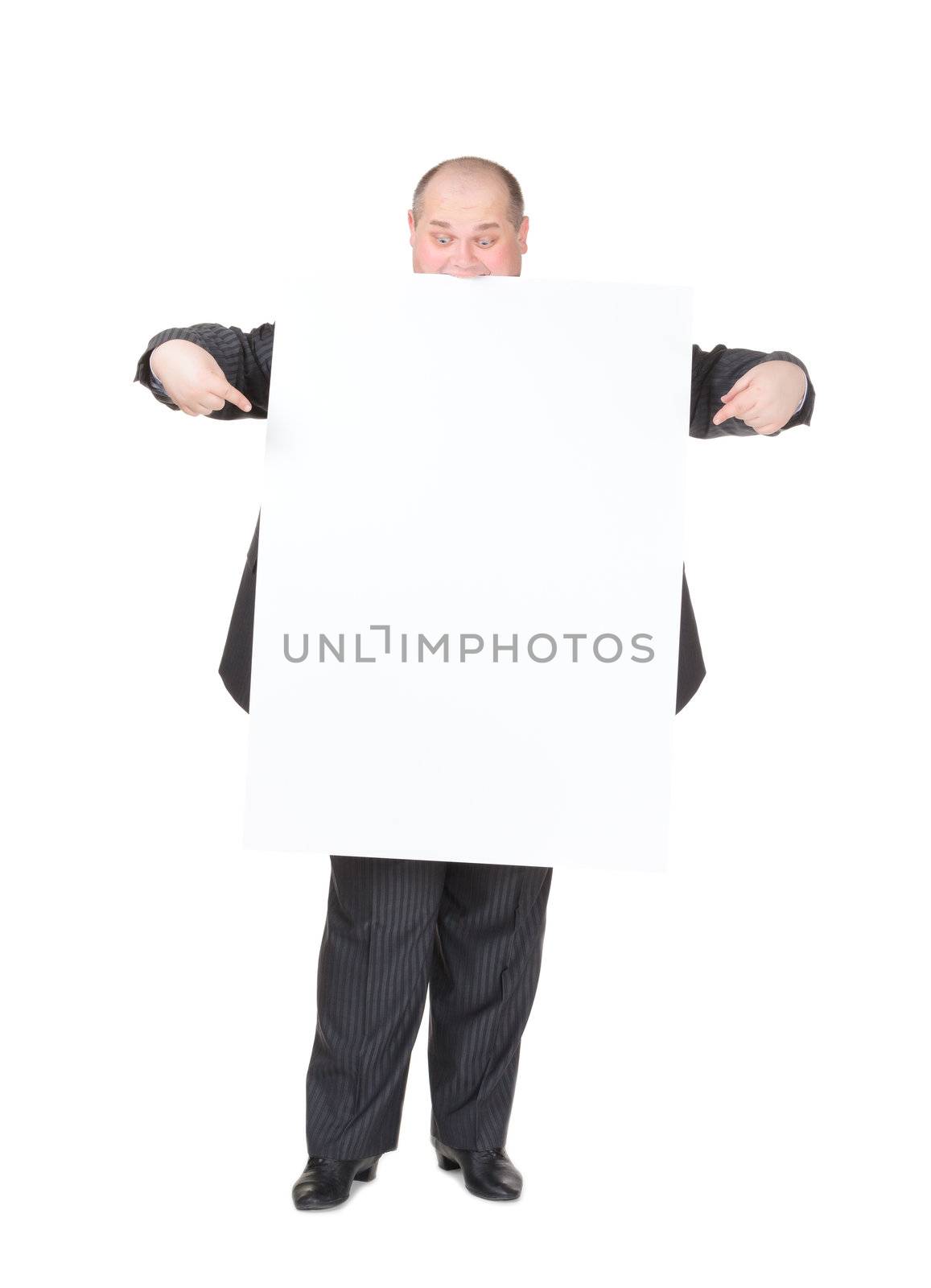 Cheerful overweight stylish business man in a suit holding up a blank white sign and pointing to it with his finger on a white studio background