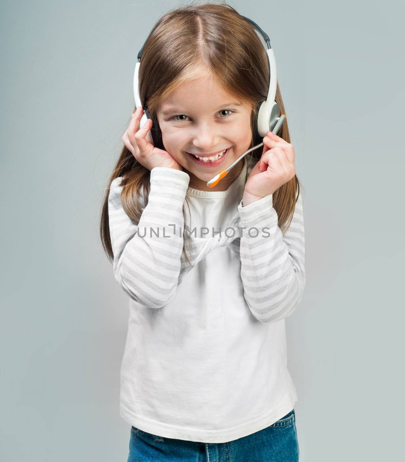 Smiling little girl in headset looks into camera