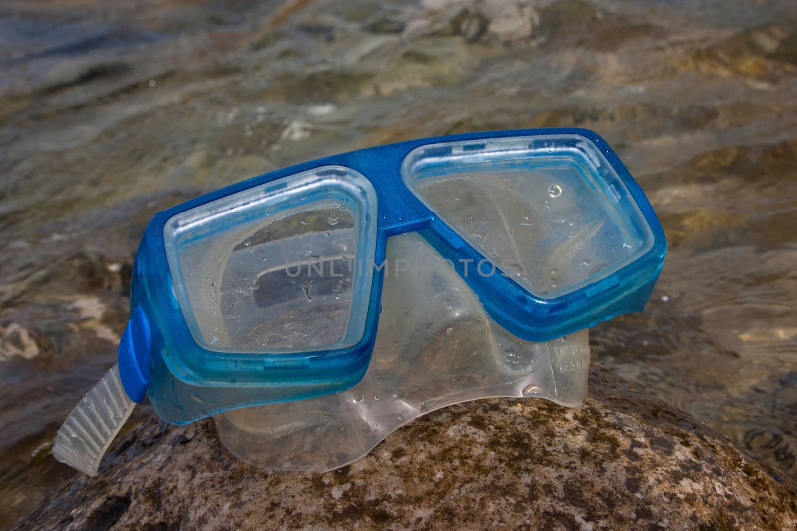 Blue snorkel goggle on a rock near the sea