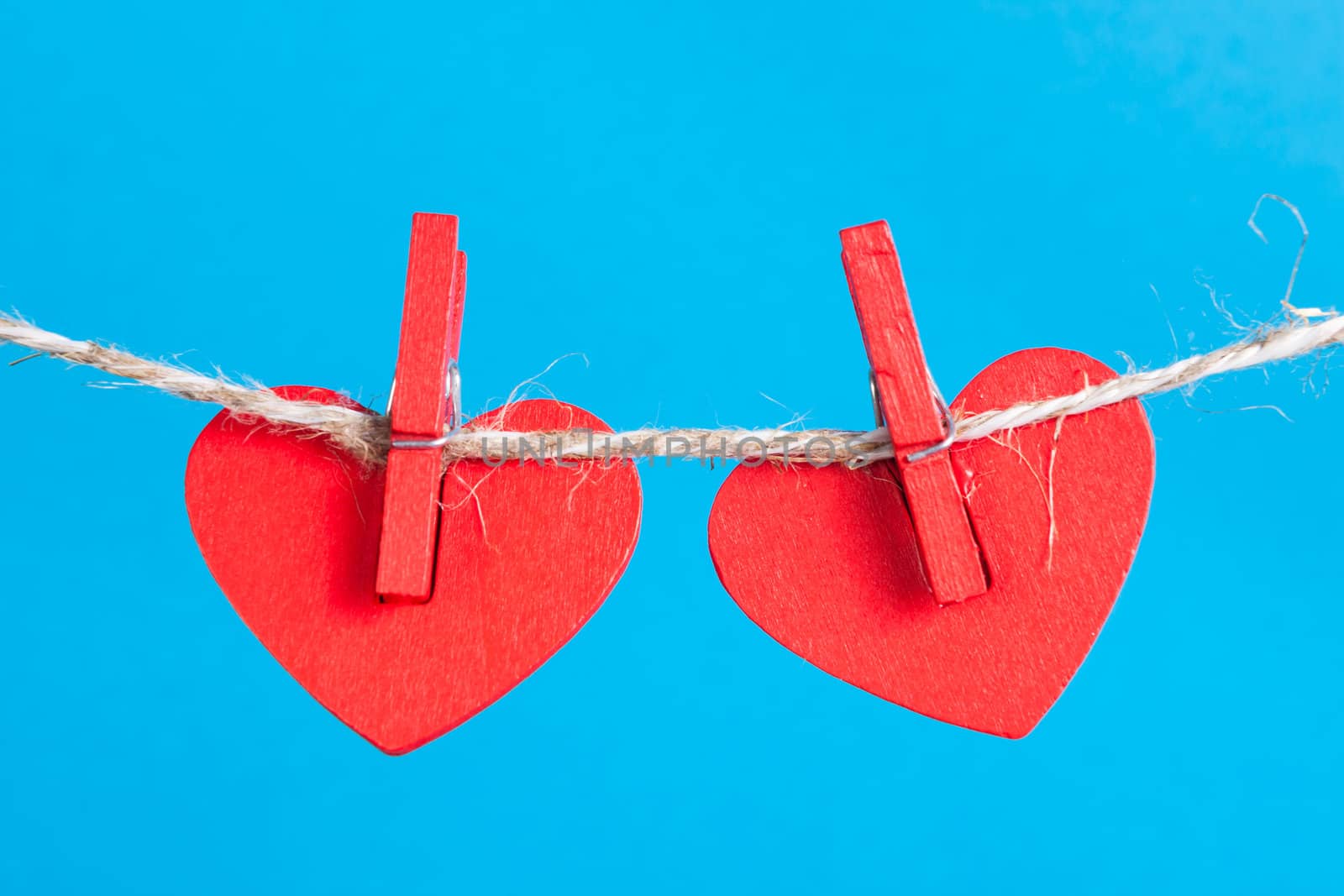 Two heart on clothesline with clothespins, blue background