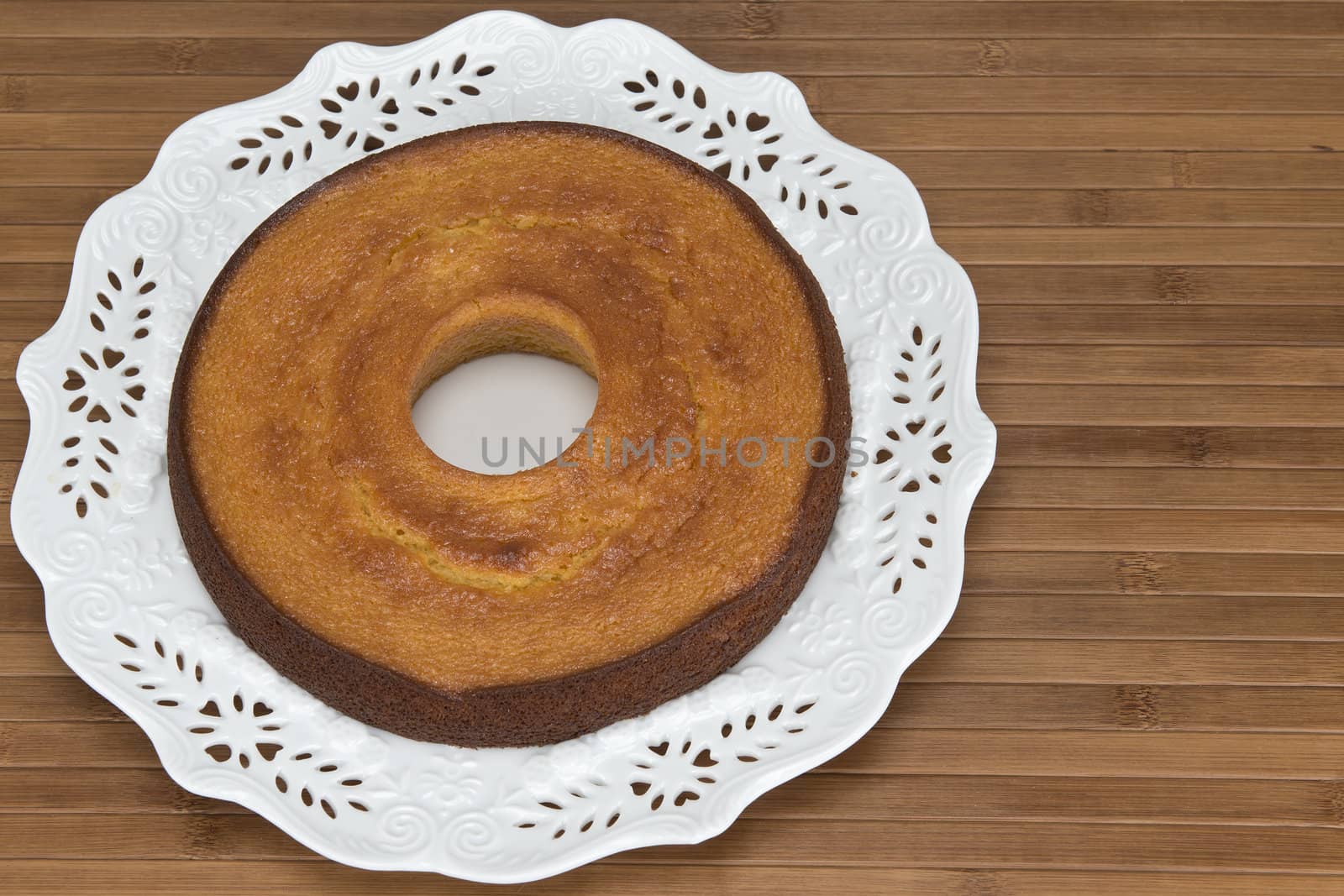 A plate with a homemade cake on a wooden surface.