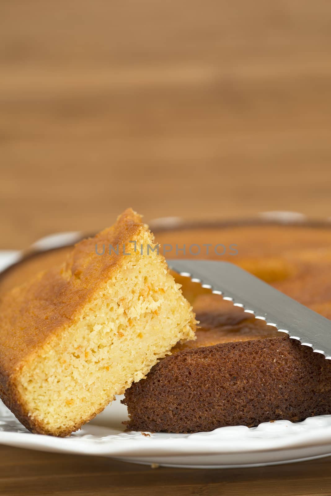 A cut homemade cake showing its texture on a wooden surface.
