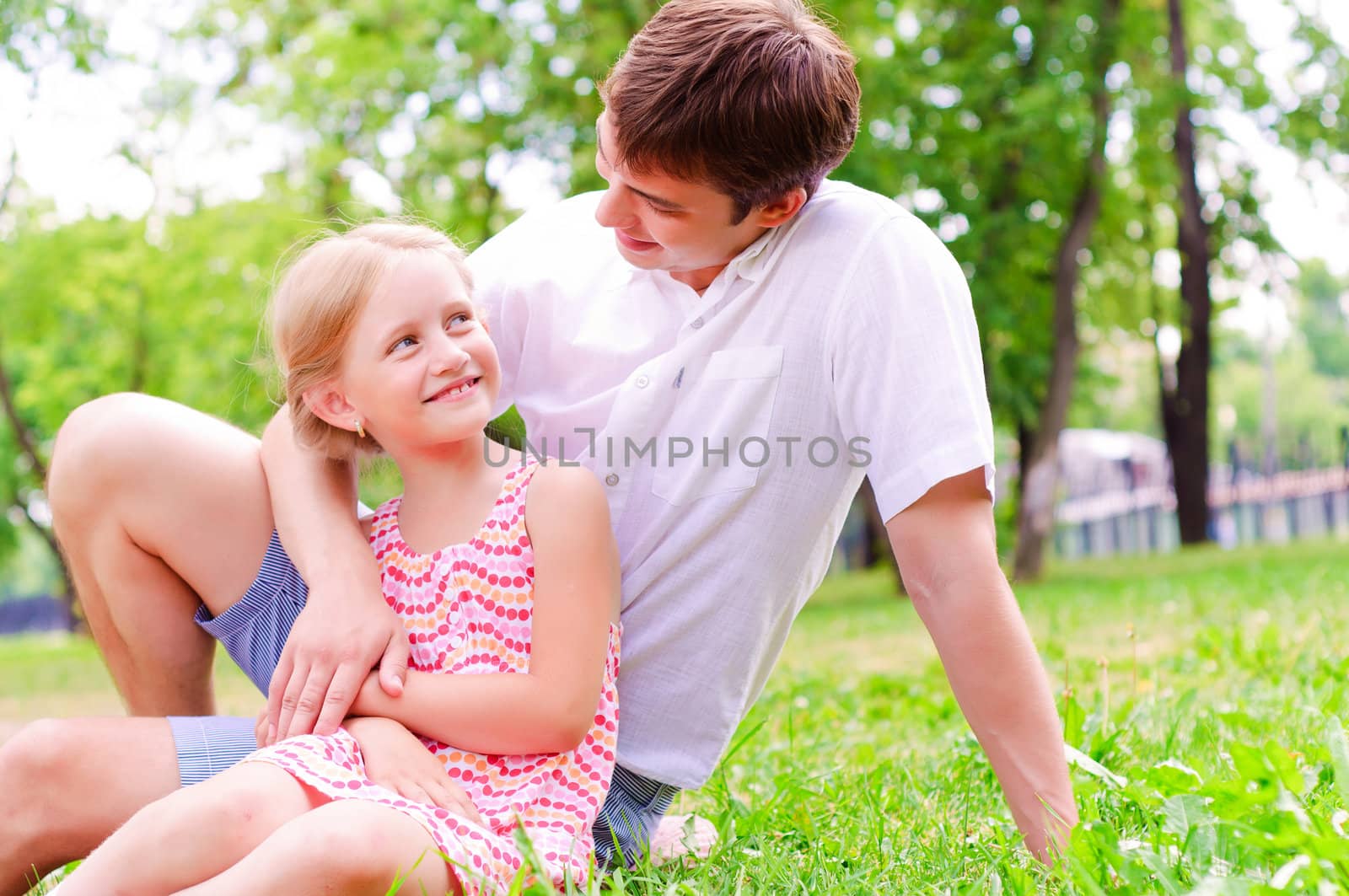 Father and daughter sitting together on the grass, and spend time with family