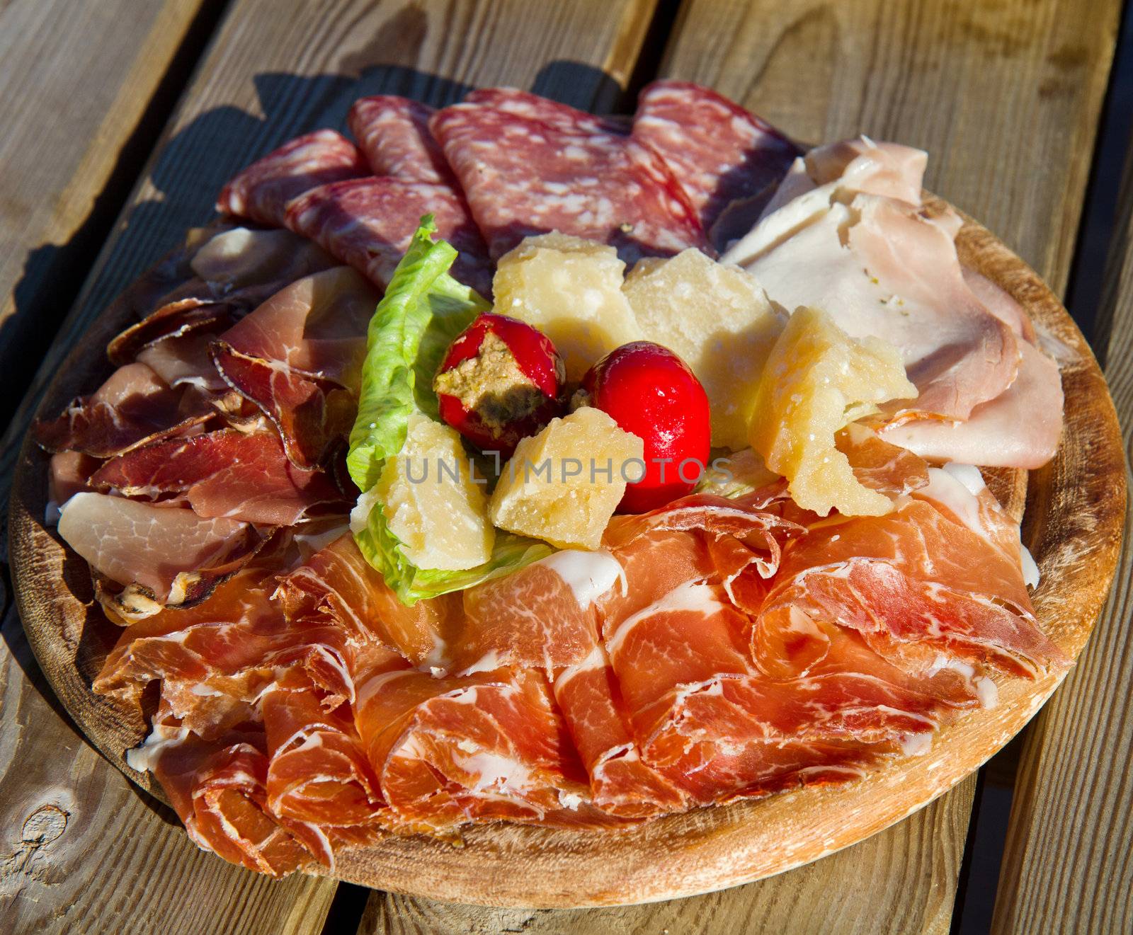 a platter of mixed cured meats, cheese on wood table