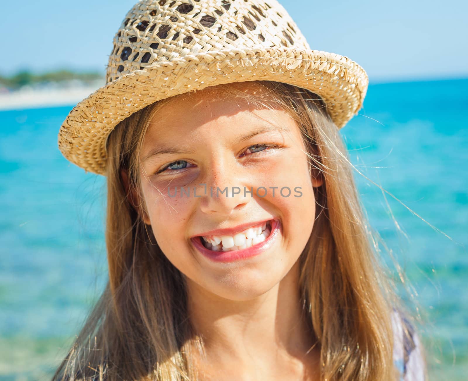 Closeup portrait of cute girl in hat on the beach
