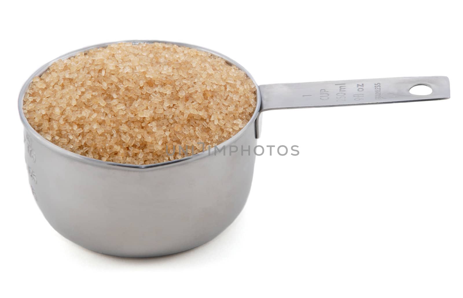 Demerara sugar presented in an American metal cup measure, isolated on a white background