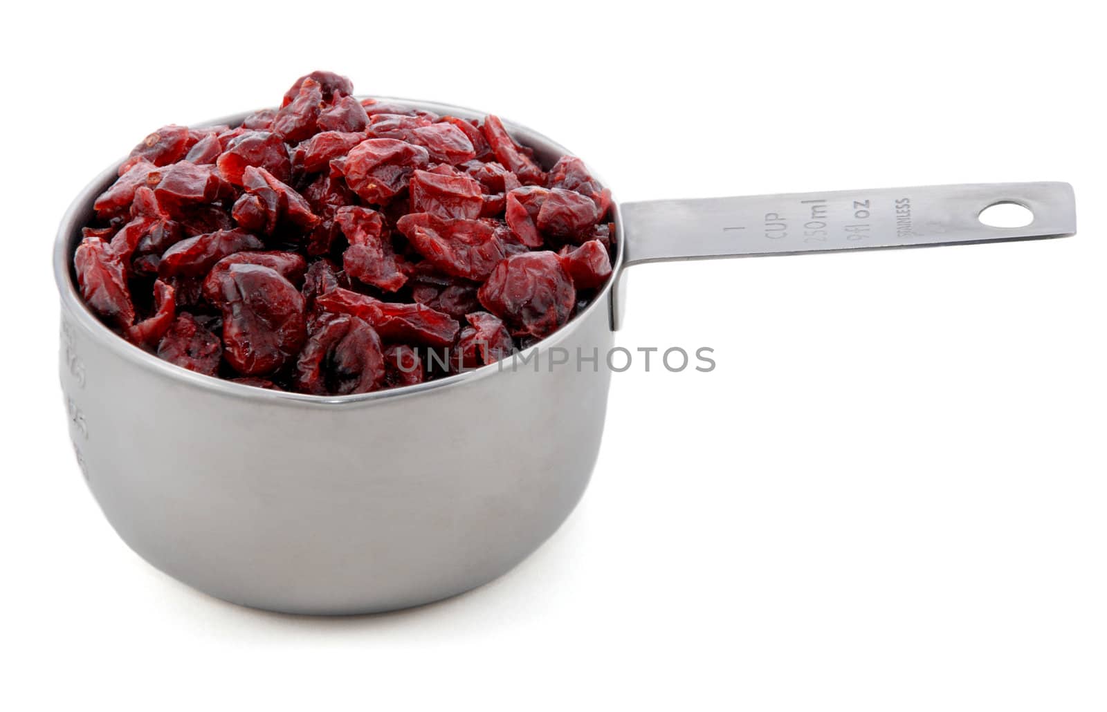 Dried cranberries presented in an American metal cup measure, isolated on a white background