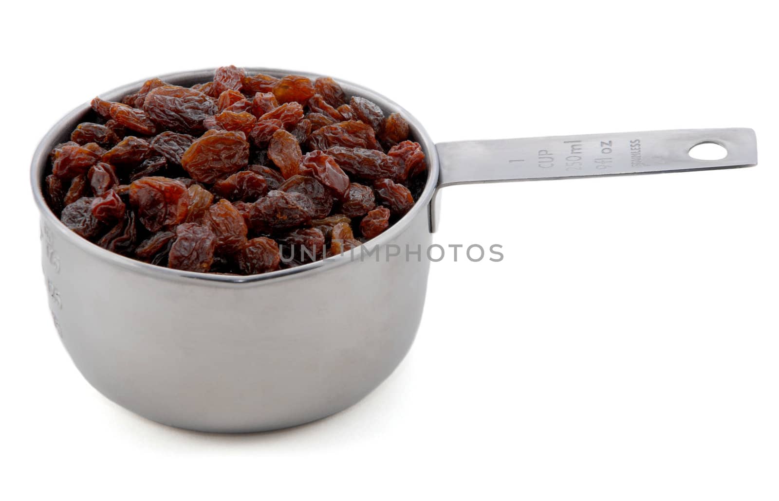 Raisins presented in an American metal cup measure, isolated on a white background