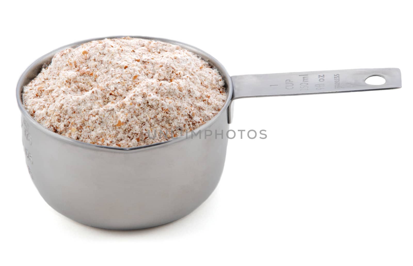 Wholemeal / wheatmeal / brown flour presented in an American metal cup measure, isolated on a white background