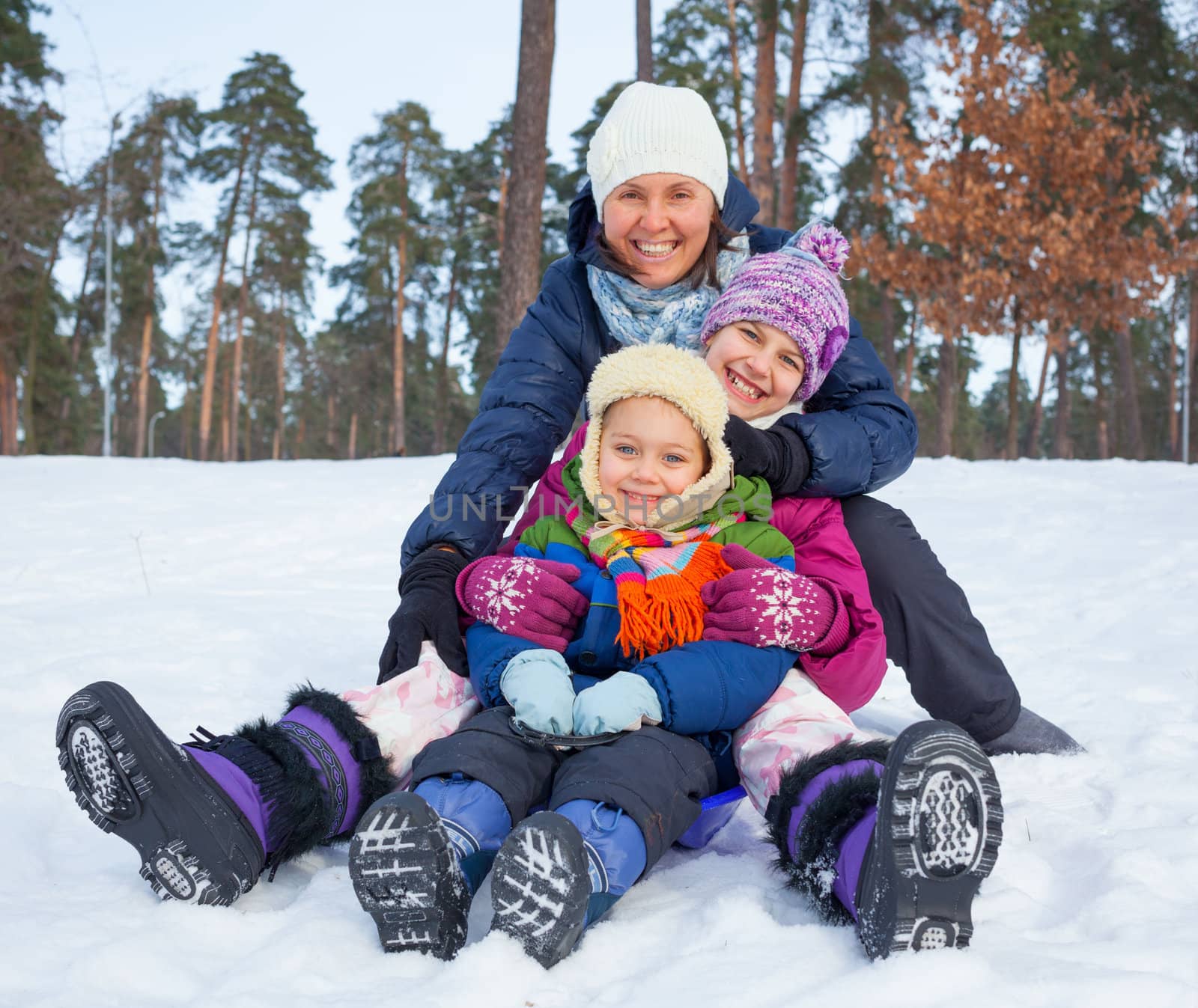 Mother with her two kids is sledging in winter-landscape