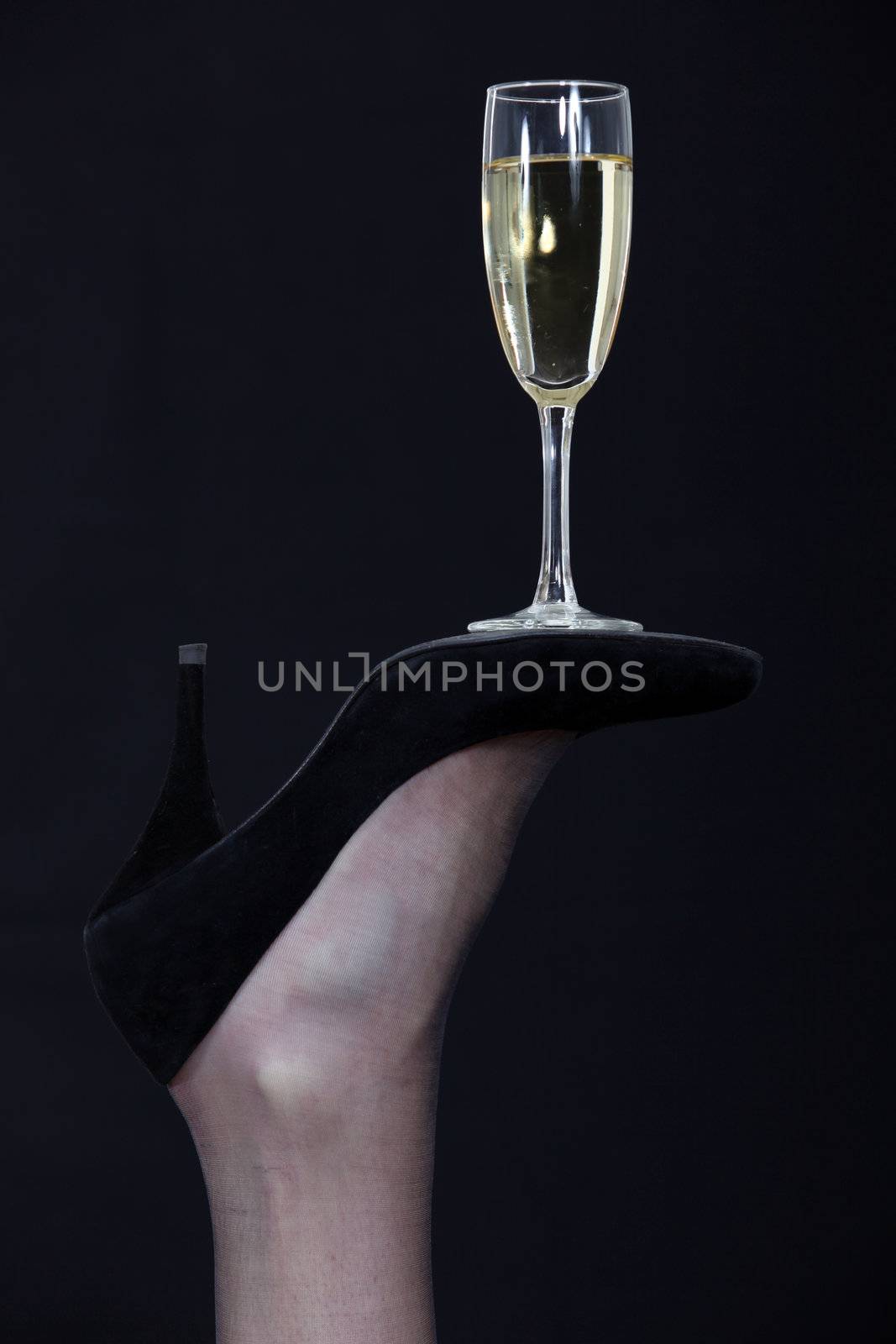 A champagne glass balanced on the sole of a shoe by phovoir