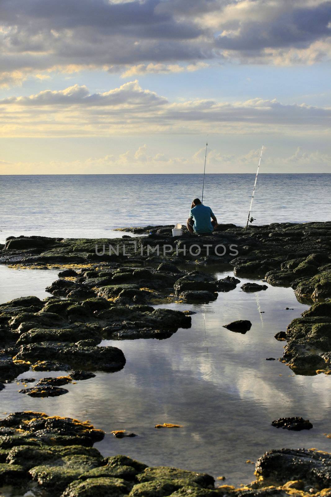 The fisherman at coast of ocean on a sunset. Mauritius