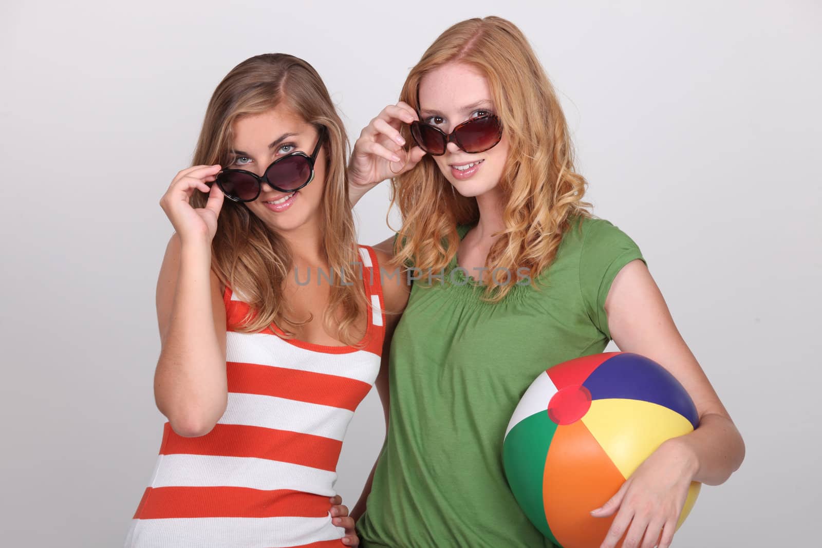 Two young woman with summer shades and a beach ball
