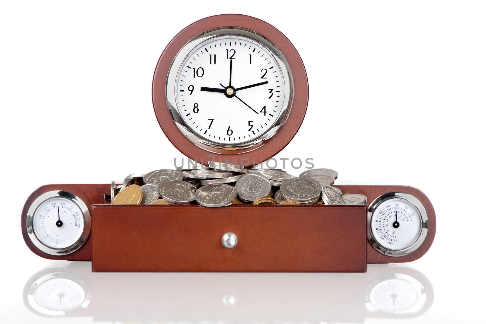 A clock with a wooden frame contains a drawer filled with coins.