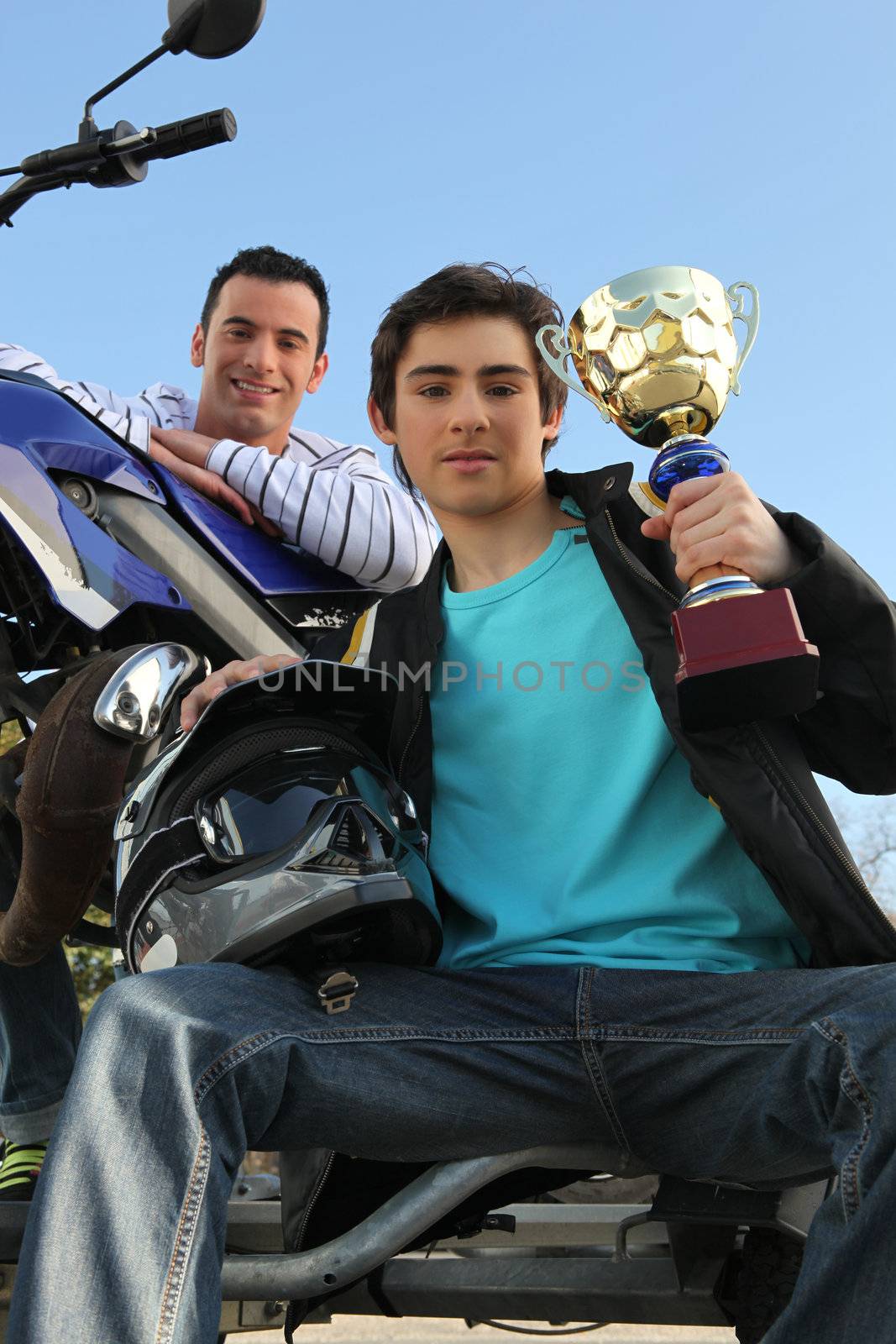 A man with a motorcycle and a trophy.