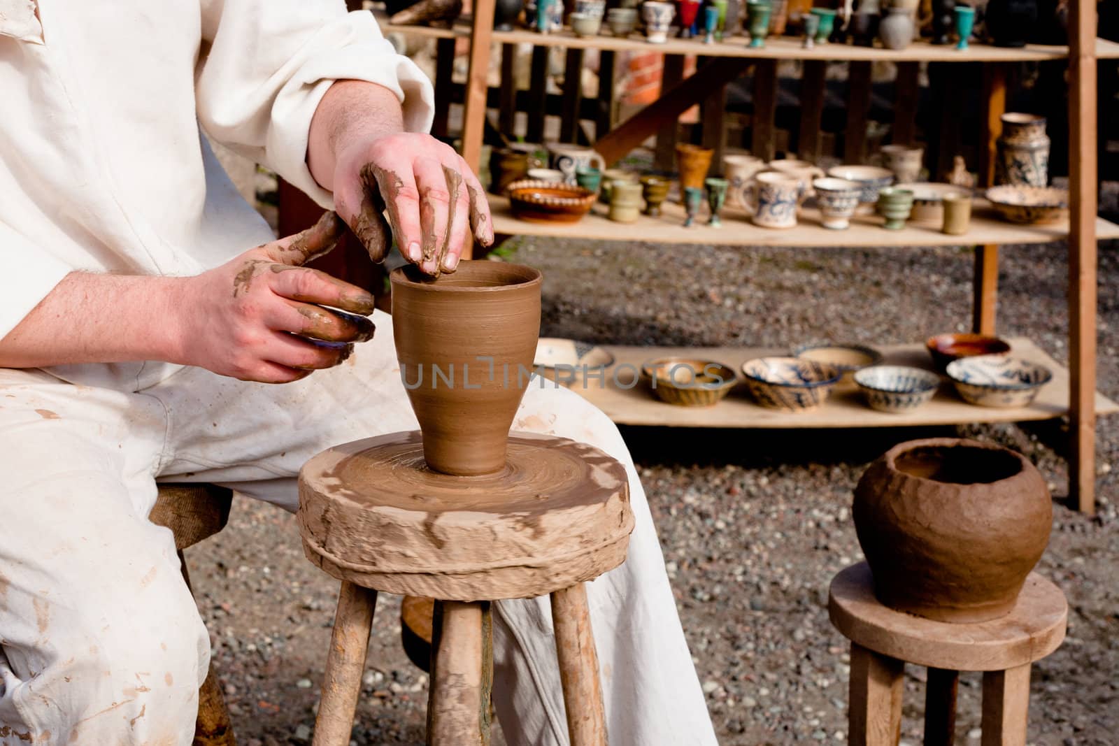 Potter in white clothes making a pot
