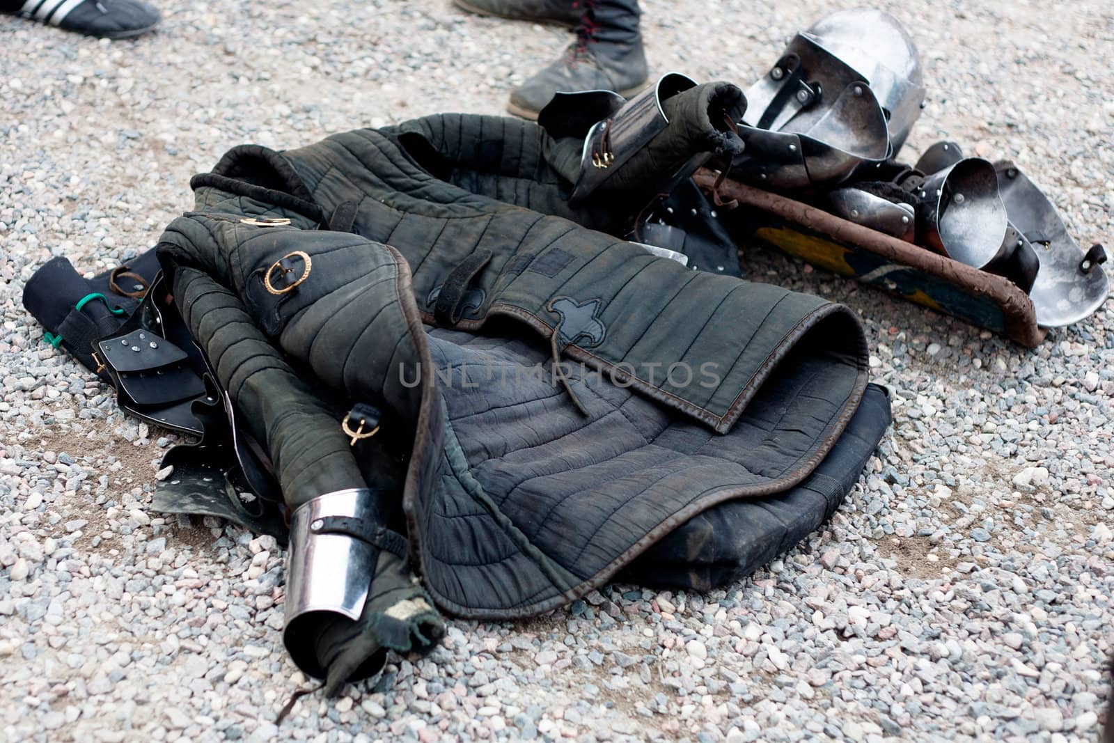Several parts of replica of medieval europian armor on gravel
