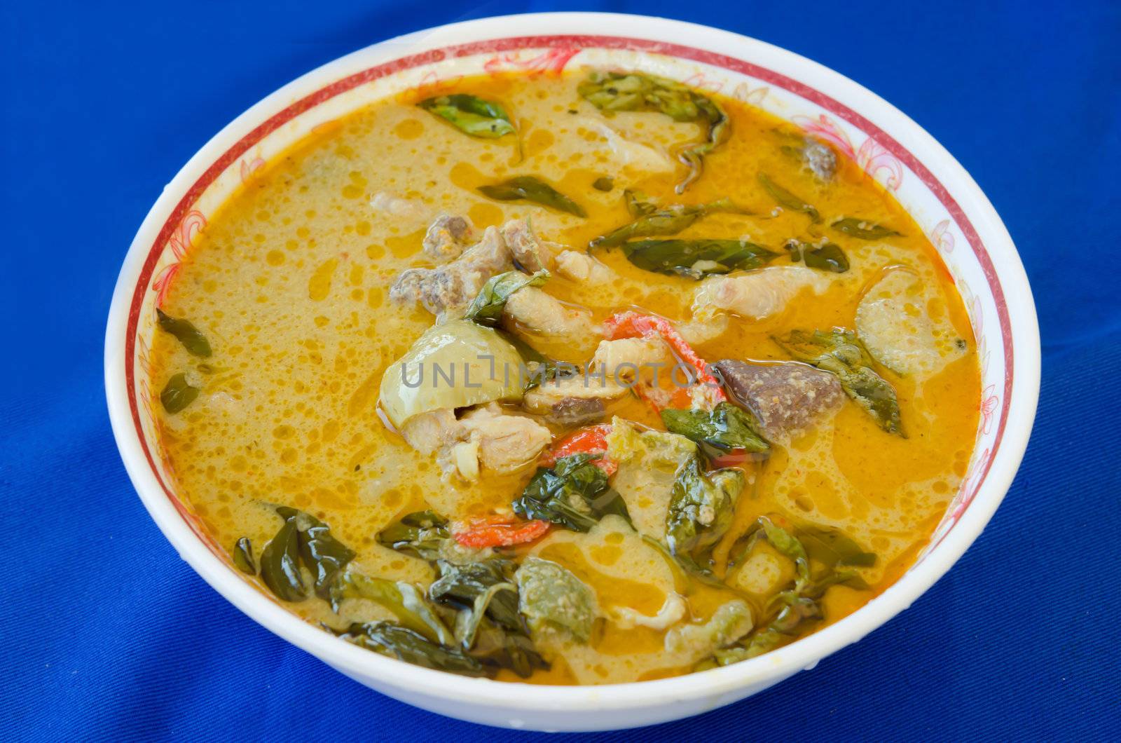 green chicken curry in bowl on blue background 