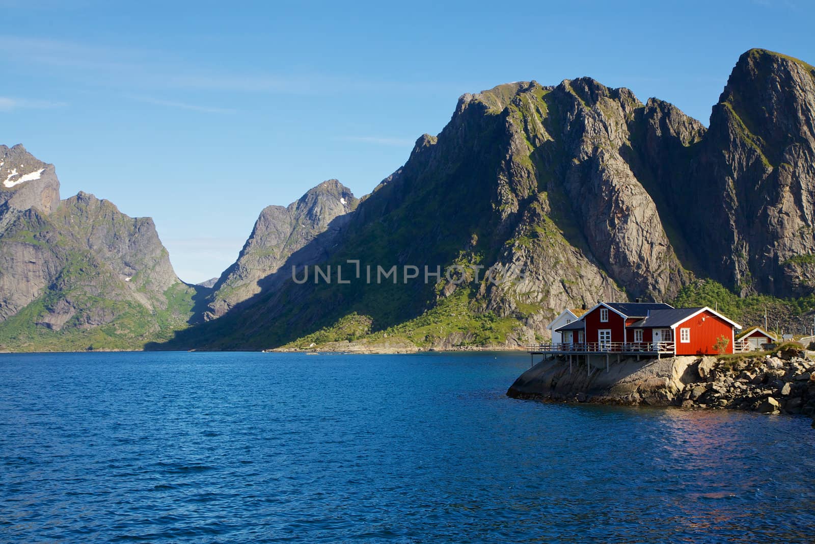 Traditional red house by scenic fjord on Lofoten islands in Norway