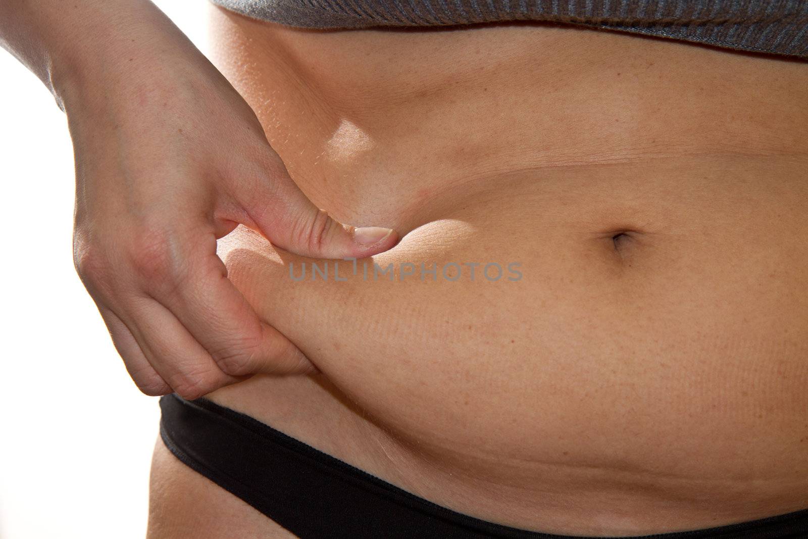 Woman's fingers measuring her belly fat