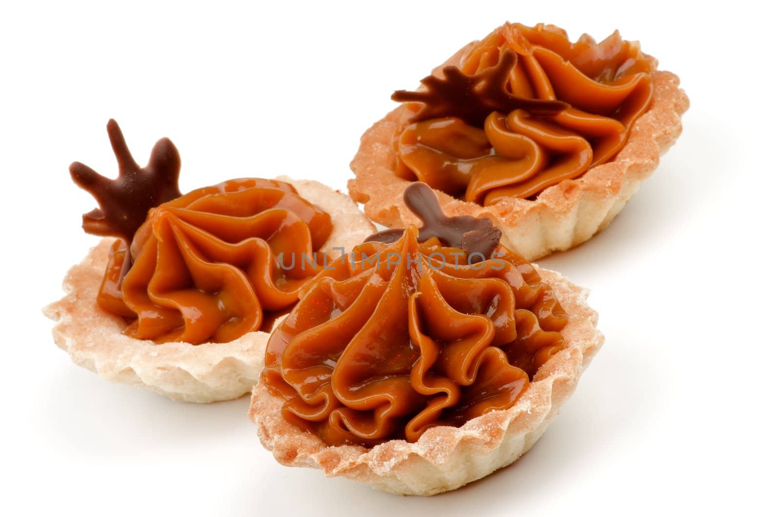 Arrangement of Delicious Little Tarts with Nougat Caramel and Chocolate Decoration isolated on white background