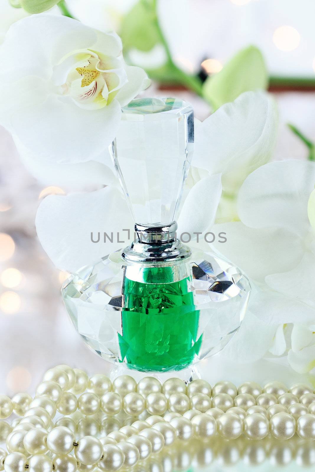 Beautiful bottle of perfume with vintage pearls and flowers.