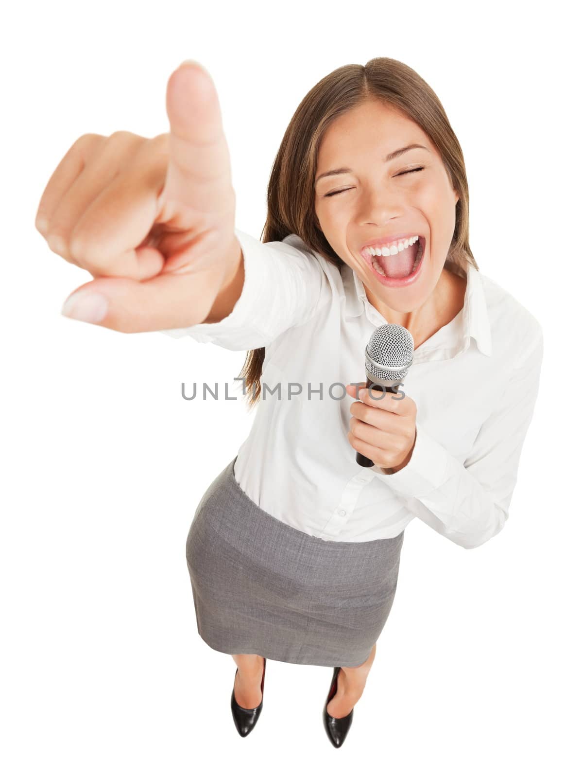 Fun high angle view of a passionate attractive young woman holding a microphone singing or making a point during a speech gesturing and pointing her finger at the camera isolated on white