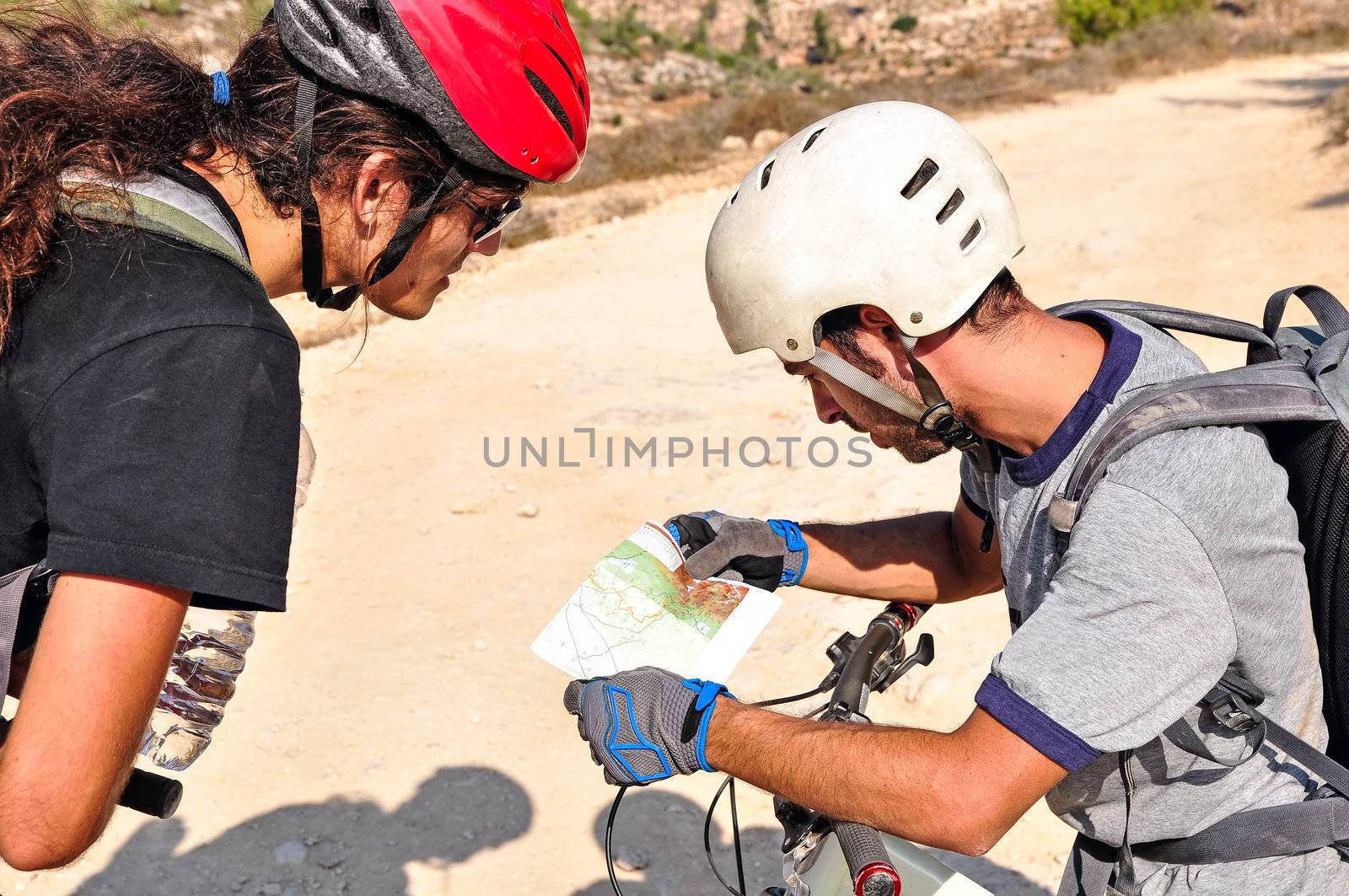 Two cyclist men read the map on the bycicle trail