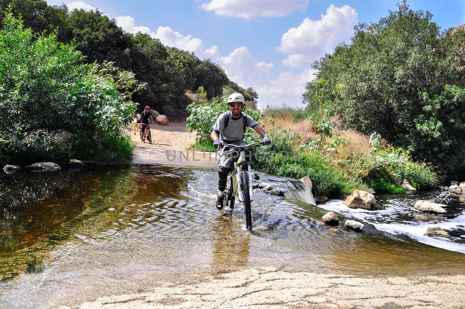 cyclist is crossing the river with a mountain bike