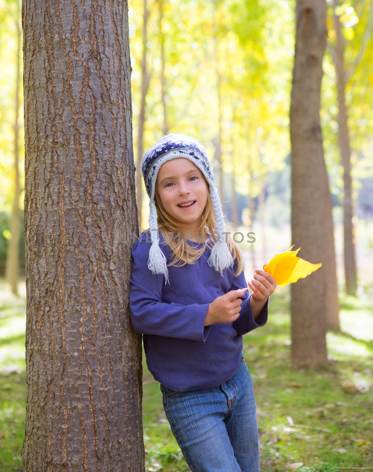Child girl in autumn poplar forest with yellow fall leaves in hand smiling happy outdoor