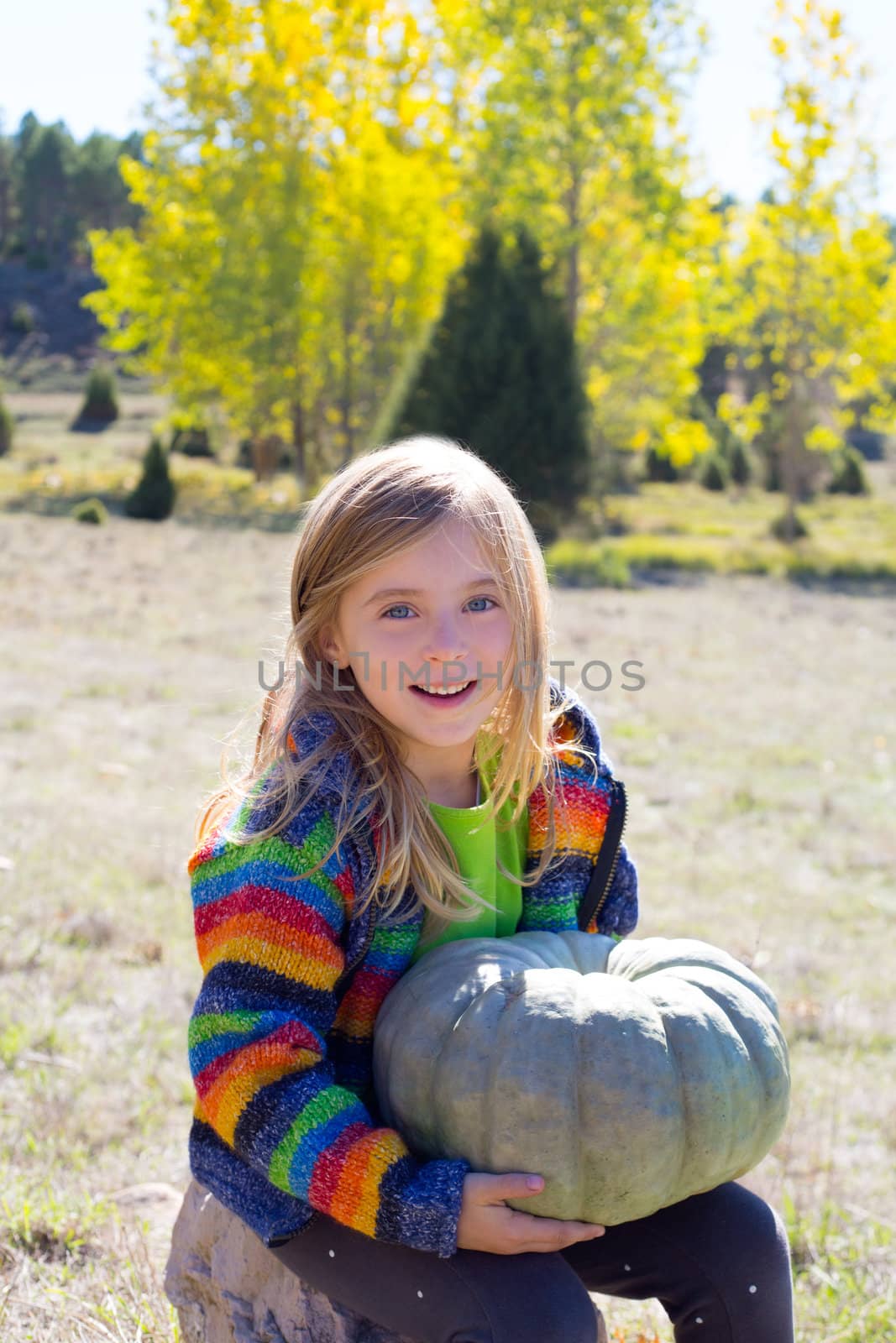 Kid little girl hoding halloween pumpkin in outdoor nature similing