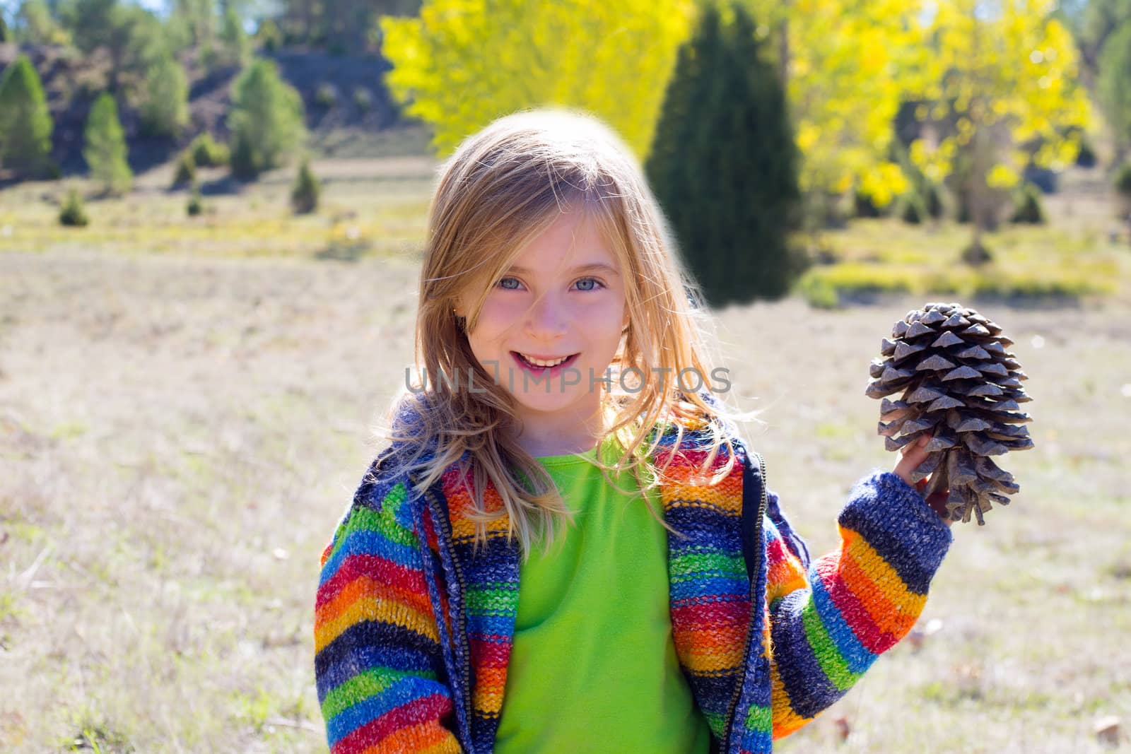 Child little girl holding pine cone in winter fall at nature outdoor