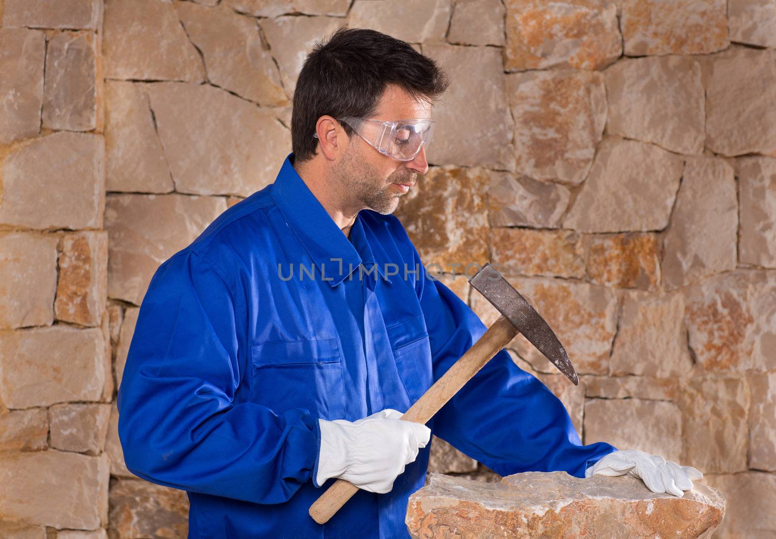 Masonry mason stonecutter man with hammer working on stone wall construction