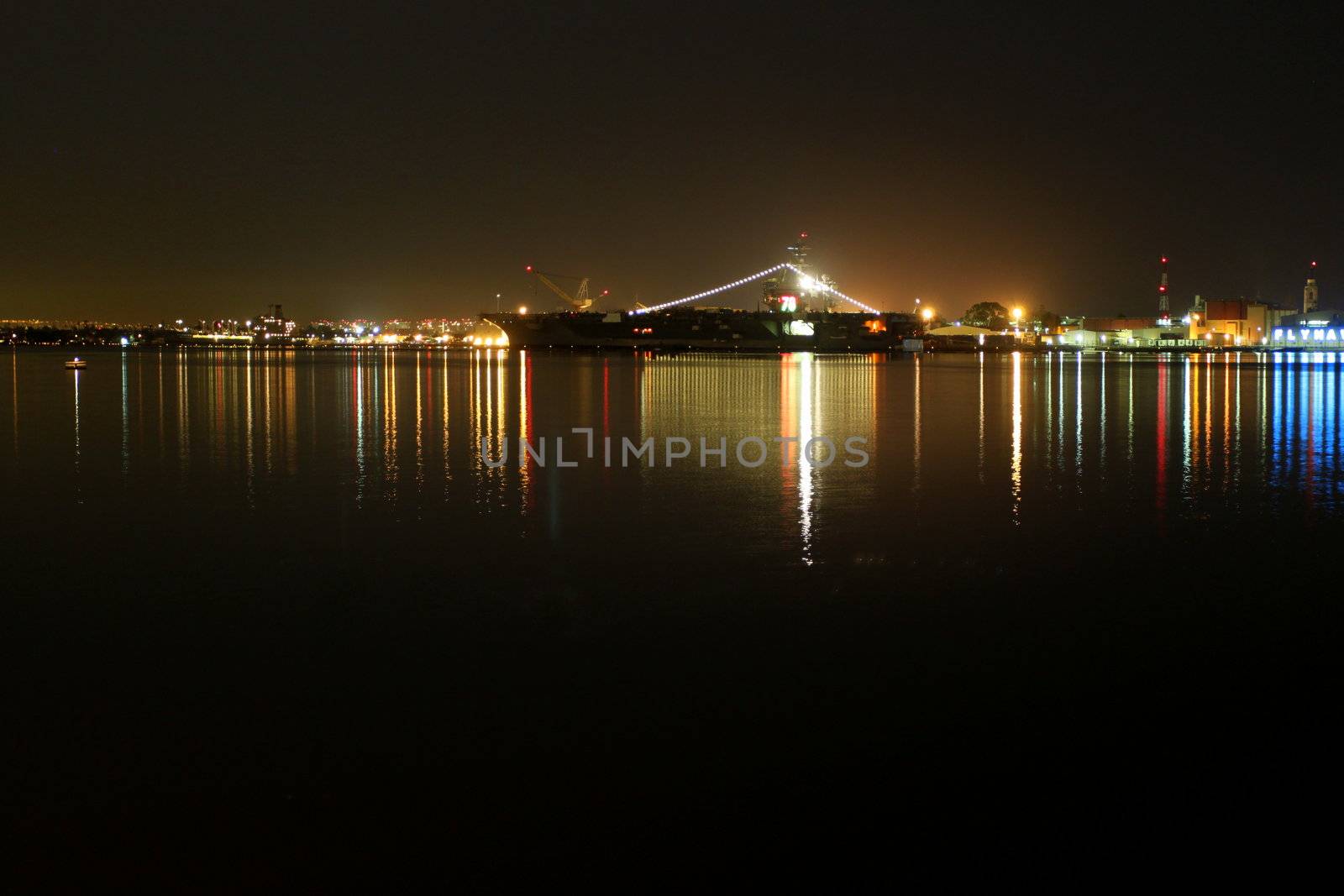 The skyline of San Diego Navy harbor at night with reflection in the water.