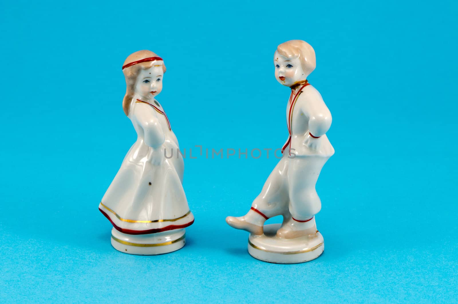 two ceramic toy decor dancers statue boy and girl on blue background.