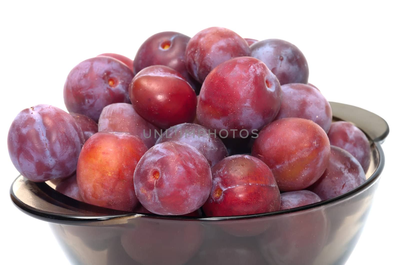 Ripe plums on a plate isolated on a white background.