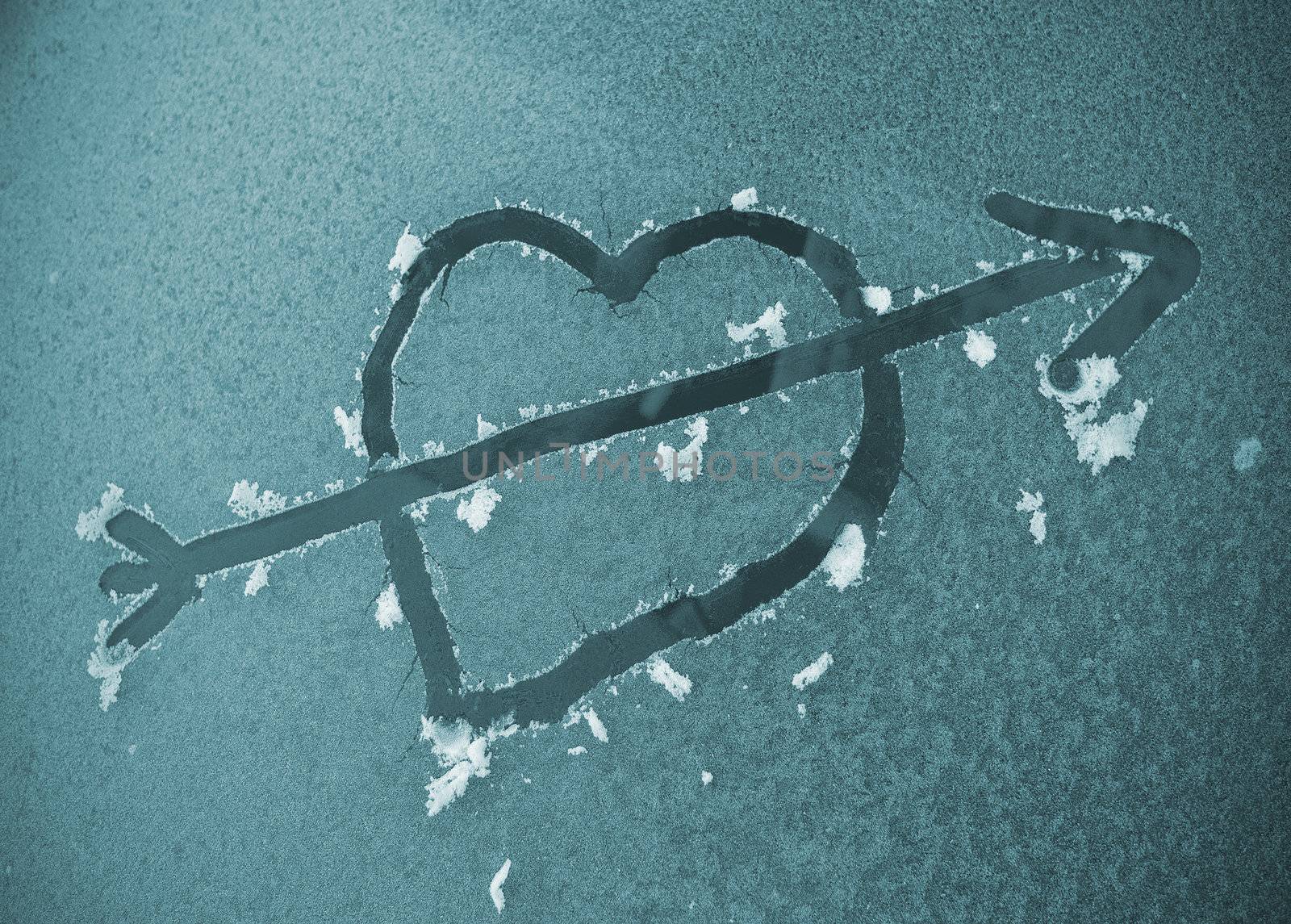 Heart with arrow scraped on a frozen automobile windscreen in the morning.