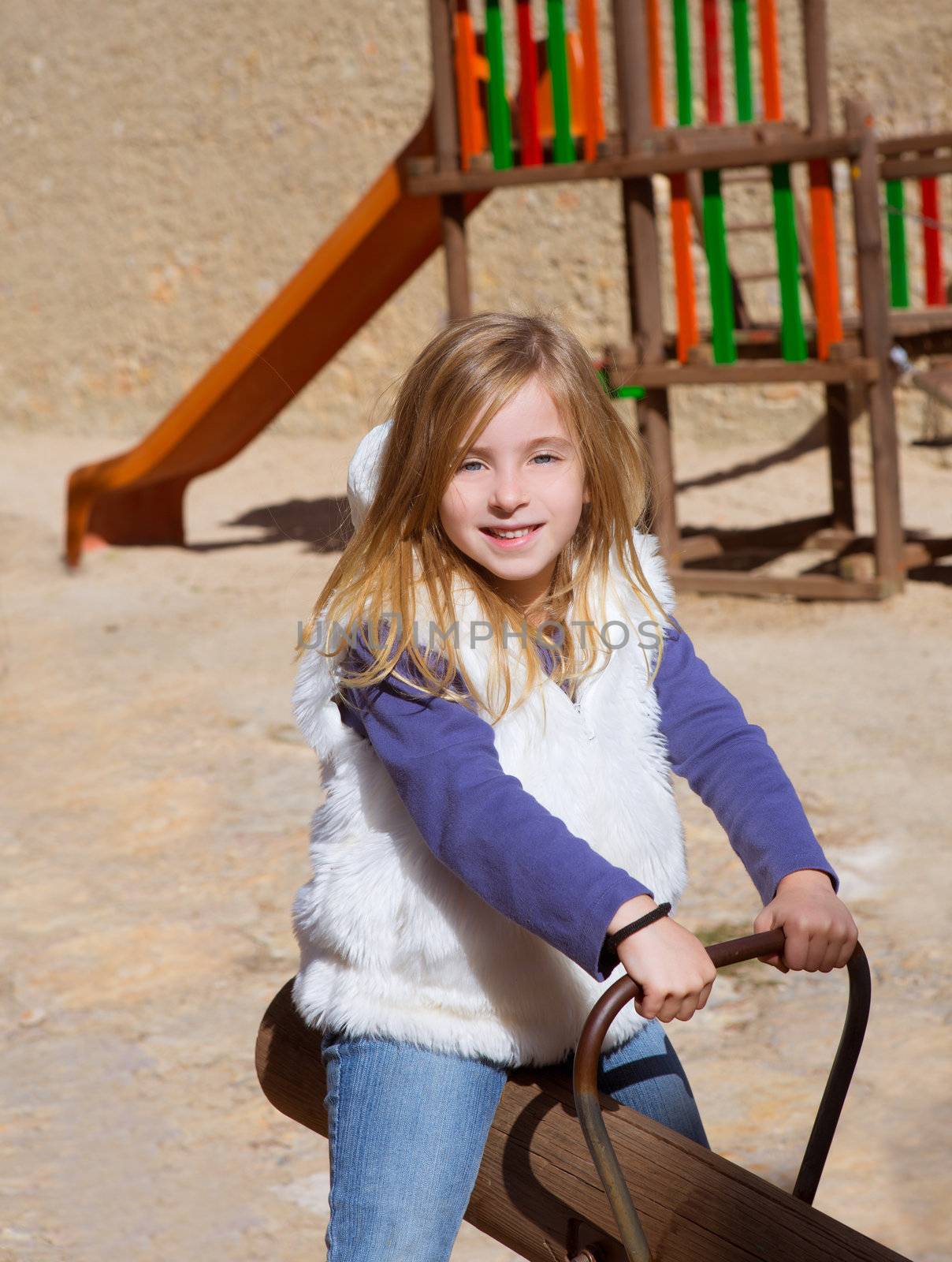 Blond child girl playing in playground smiling on swing by lunamarina