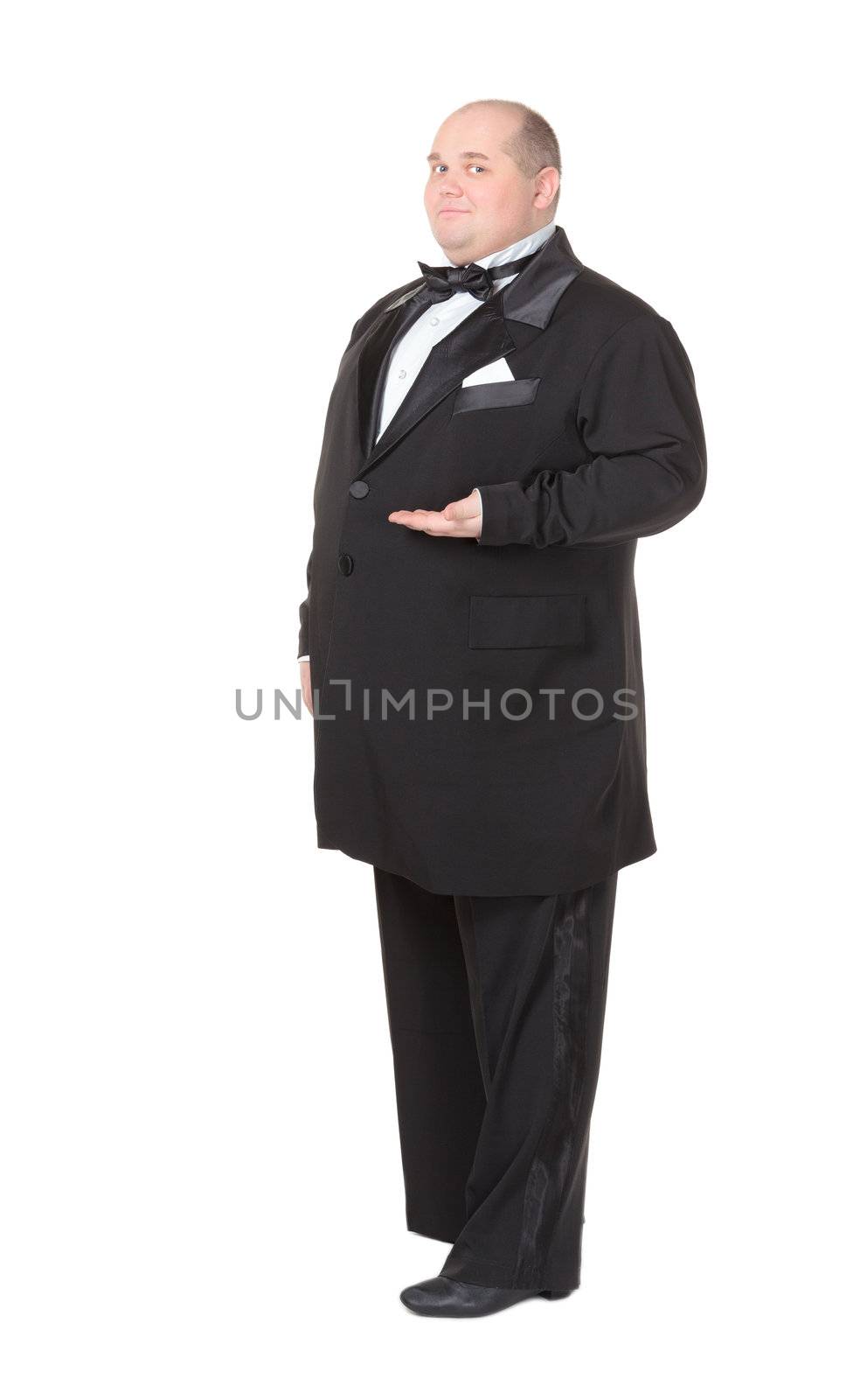 Elegant very fat man in a dinner jacket and bow tie winking mischievously and pointing with his finger across his belly , three quarter studio portrait on white