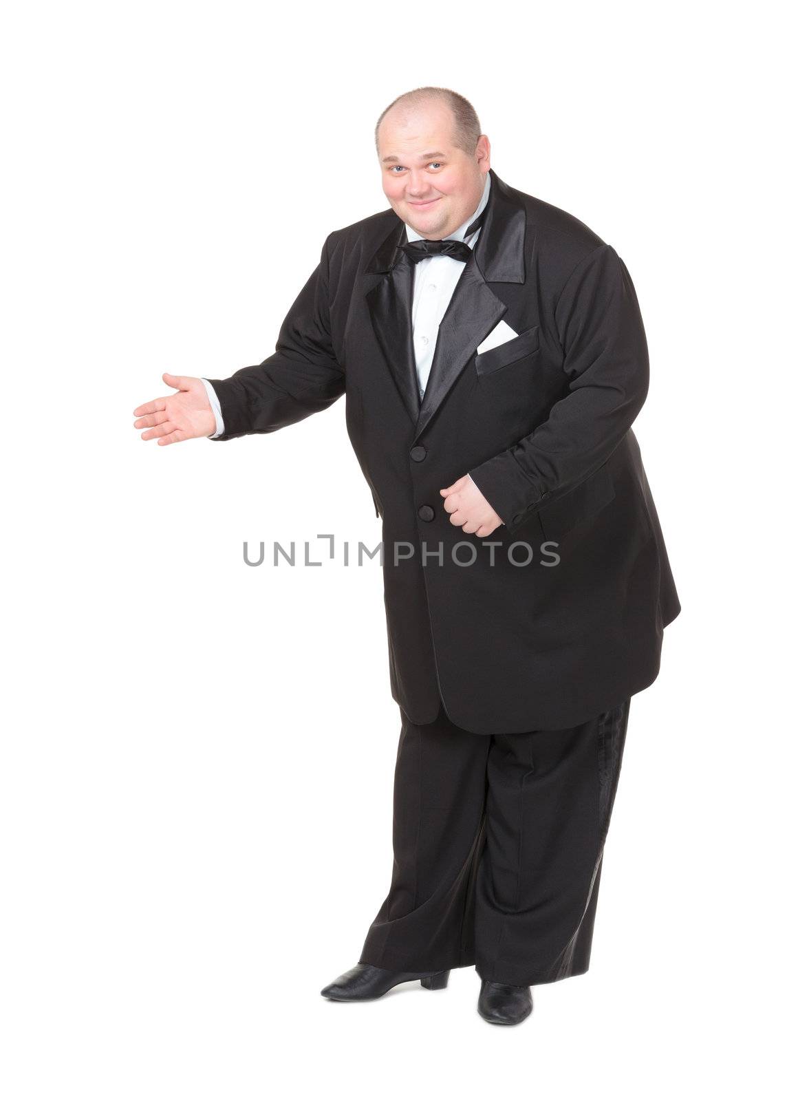 Elegant fat man in a dinner jacket and bow tie smiling charmingly as he holds out his hand to the side gesturing in that direction