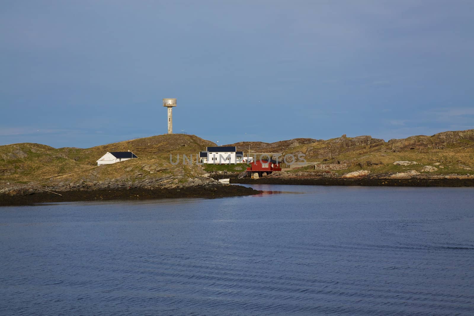 Scenic rocky coastline of island Rost in Norway with houses and old lighthouse