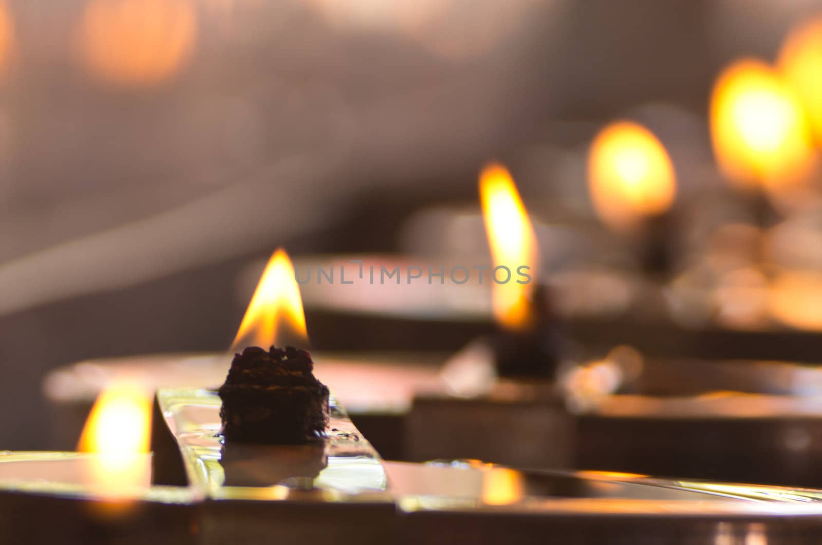Group of burning candles on black background.
