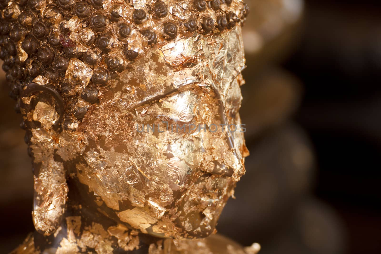 Gold face of statue Buddha with gold leaf attached