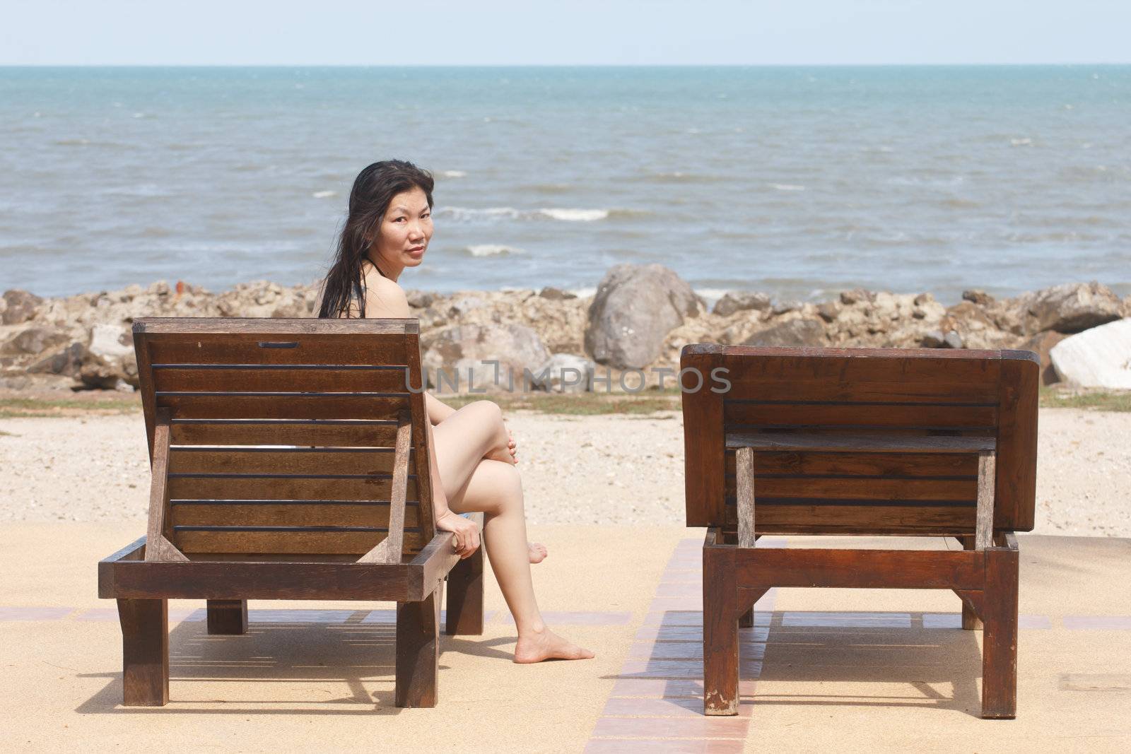 Women sit on the benches on the beach.