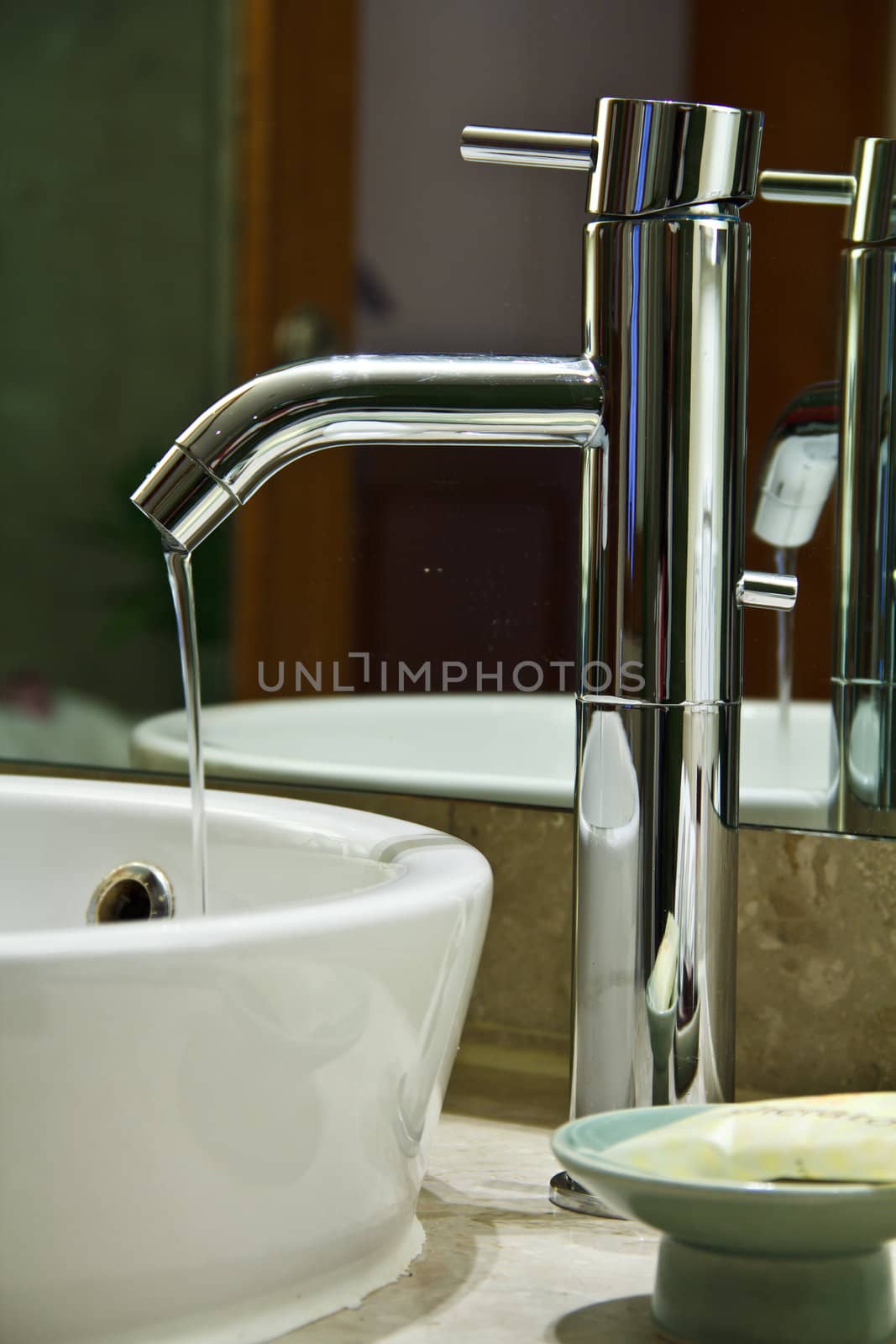 Silver chrome bathroom tap faucets running water in a sink